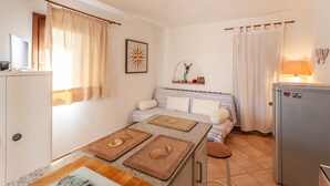 Una habitación compacta con cama, mesita de noche y una pequeña cocina.