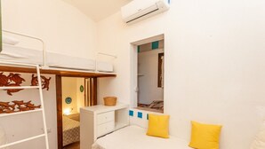 Habitación compacta con literas, una cama individual, un escritorio y una ventana.