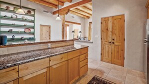Una cocina con armarios de madera, encimeras de granito y techo de madera.