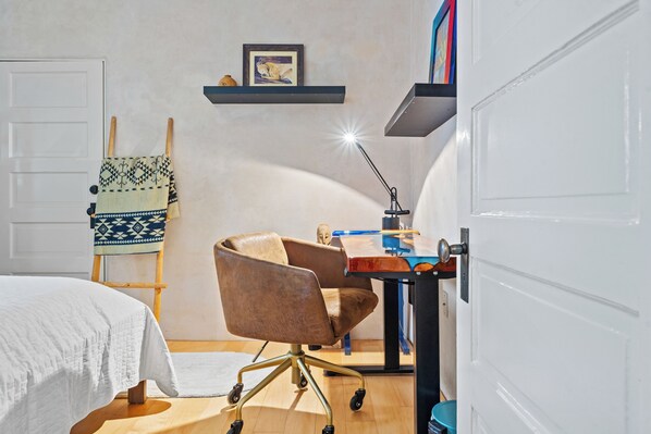 A bedroom with a bed, a desk, a chair, a lamp, a shelf with a picture, and a ladder. - Casa Colores | Stylish Retreat (Santa Fe)