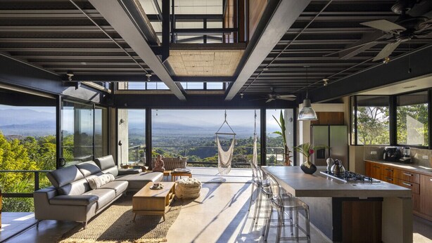 A modern kitchen with a large island, a dining area with a hanging chair, and a sofa. - Zen Jungle Oasis ~ Infinity Pool ~ Stunning Views (Quepos)