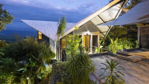 A modern house with a sloped roof, surrounded by lush tropical vegetation. - Zen Jungle Oasis ~ Infinity Pool ~ Stunning Views (Quepos)