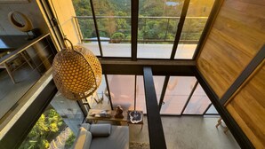 A modern interior with a large window offering a scenic view of a forested landscape. - Zen Jungle Oasis ~ Infinity Pool ~ Stunning Views (Quepos)