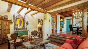 A rustic interior with wooden beams, a large painting, and a cozy seating area.