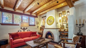 A cozy living room with a red sofa, wooden coffee table, and a fireplace.