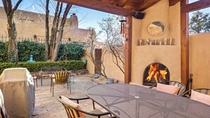An outdoor patio with a round metal table and chairs, a covered grill, and a fire feature. - Casa Segunda | Elegant Santa Fe Retreat (Santa Fe)