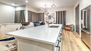 Une cuisine moderne dotée d’un îlot central, d’appareils électroménagers en acier inoxydable et d’un coin repas avec une table ronde et des chaises.