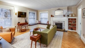 Ein Wohnzimmer mit einem grünen Sofa, einem Holztisch und einem Kamin.