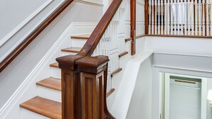 Eine Treppe mit Holzstufen und einem Holengeländer, die zu einer oberen Etage mit Blick auf einen Küchenbereich führt.
