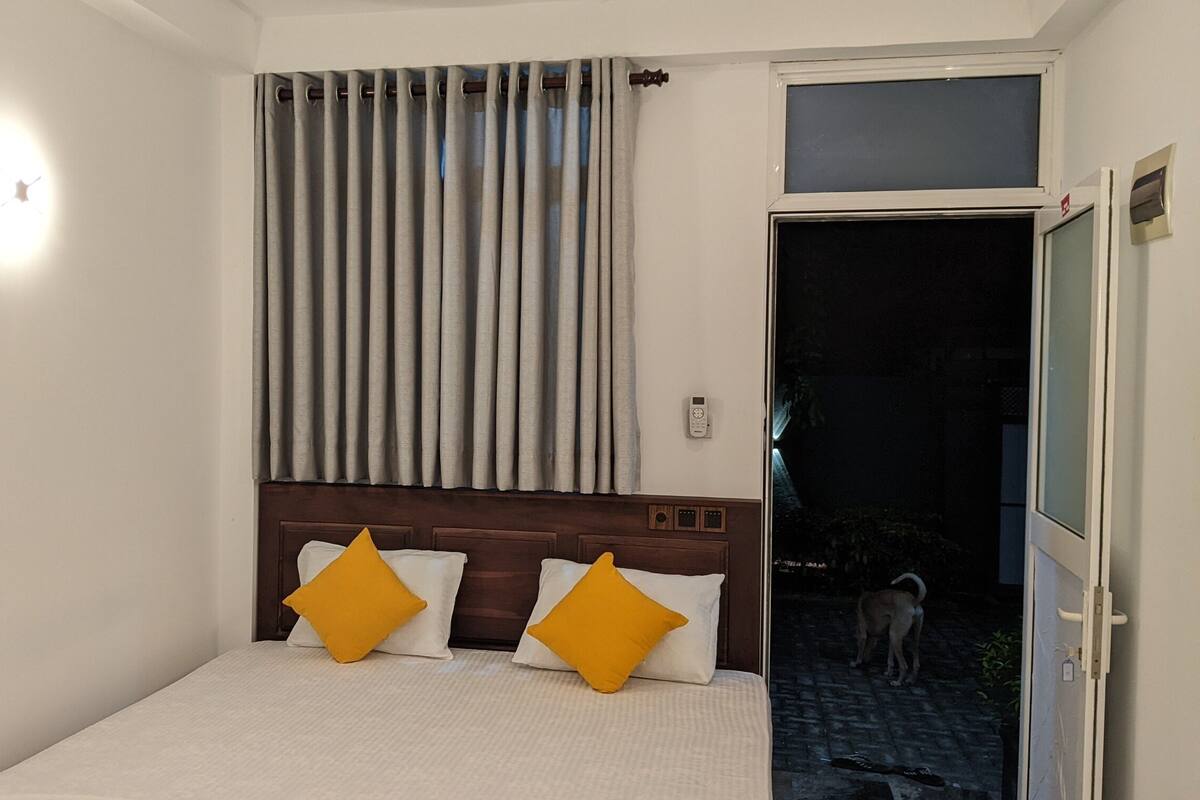 A bedroom with a bed, curtains, a window, and a door leading outside.