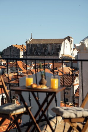 Enjoy a serene moment on this terrace overlooking a historic town with a stunning view of the church and traditional buildings.