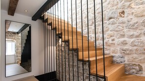 A staircase with wooden steps and black metal railings, leading to a stone wall.