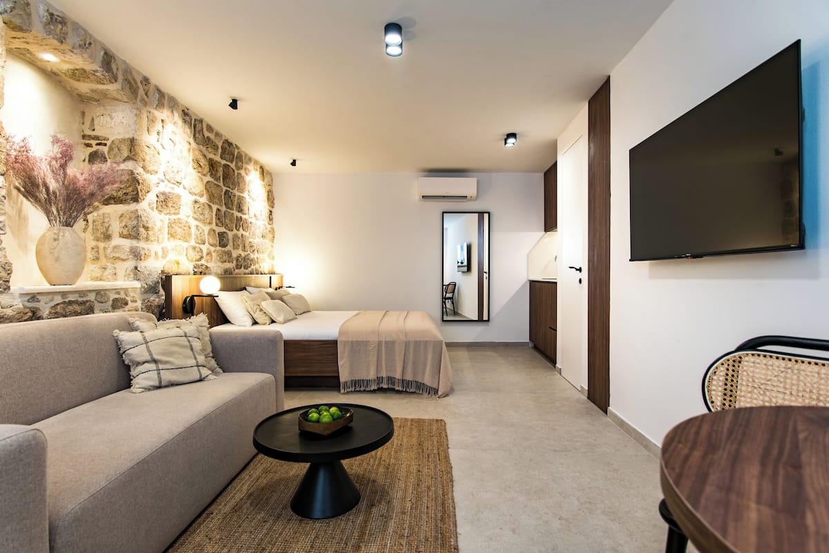 Una sala de estar moderna con una pared de acento de piedra, un sofá, una mesa de centro y un televisor de pantalla plana.