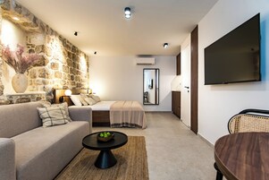 Uma sala de estar moderna com parede de destaque em pedra, um sofá, uma mesa de centro e uma TV de tela plana.