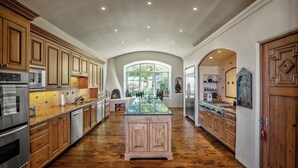 A spacious kitchen with wooden cabinets, a central island, and a large window providing natural light. - Villa Campanas | Luxury Home with Mountain Views (Santa Fe)