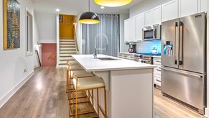A modern kitchen with a central island, stainless steel appliances, and pendant lighting. - Two New Lux Homes! Rooftop + Hot Tub, Pool & Sauna (Nashville)