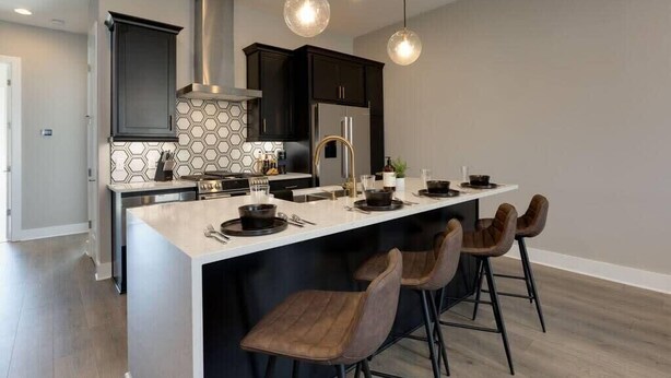 A modern kitchen with dark cabinets, a white island, and pendant lighting. - 2 Lux Homes, 8 bedrooms/28 beds! Baller Game Room (Nashville)