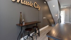 A modern interior with a dark wall, a wooden bar area, and a sign that reads "Music City". - 2 Lux Homes, 8 bedrooms/28 beds! Baller Game Room (Nashville)