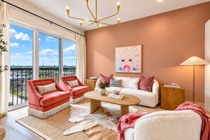 A modern living room with a large window, two red armchairs, a white sofa, a coffee table, and a floor lamp. - Dolly Parton Retreat Lux Home on Main St! 11 beds! (Nashville)