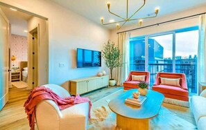 A modern living room with a large window, a TV, and a potted plant.