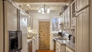 Een smalle keuken met een ingebouwde oven, een houten deur en een raam.