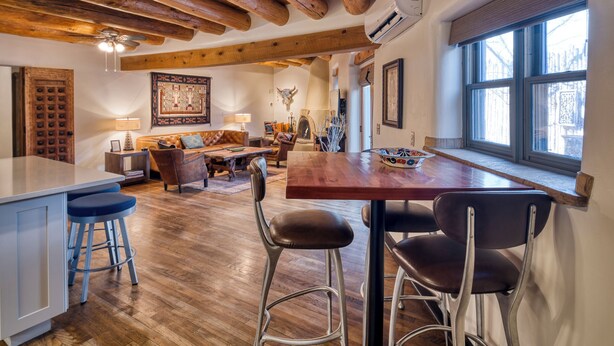 A spacious kitchen with wooden beams, a dining area with a large table and chairs, and a bar area with stools.