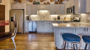 A modern kitchen with wooden beams, stainless steel appliances, and a central island with bar stools.