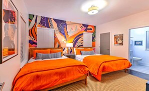 A hotel room with two beds, a colorful abstract mural on the wall, a framed picture, and a poster. - Lux Designer Gulch Home - Skyline Views - 11 Beds! (Nashville)