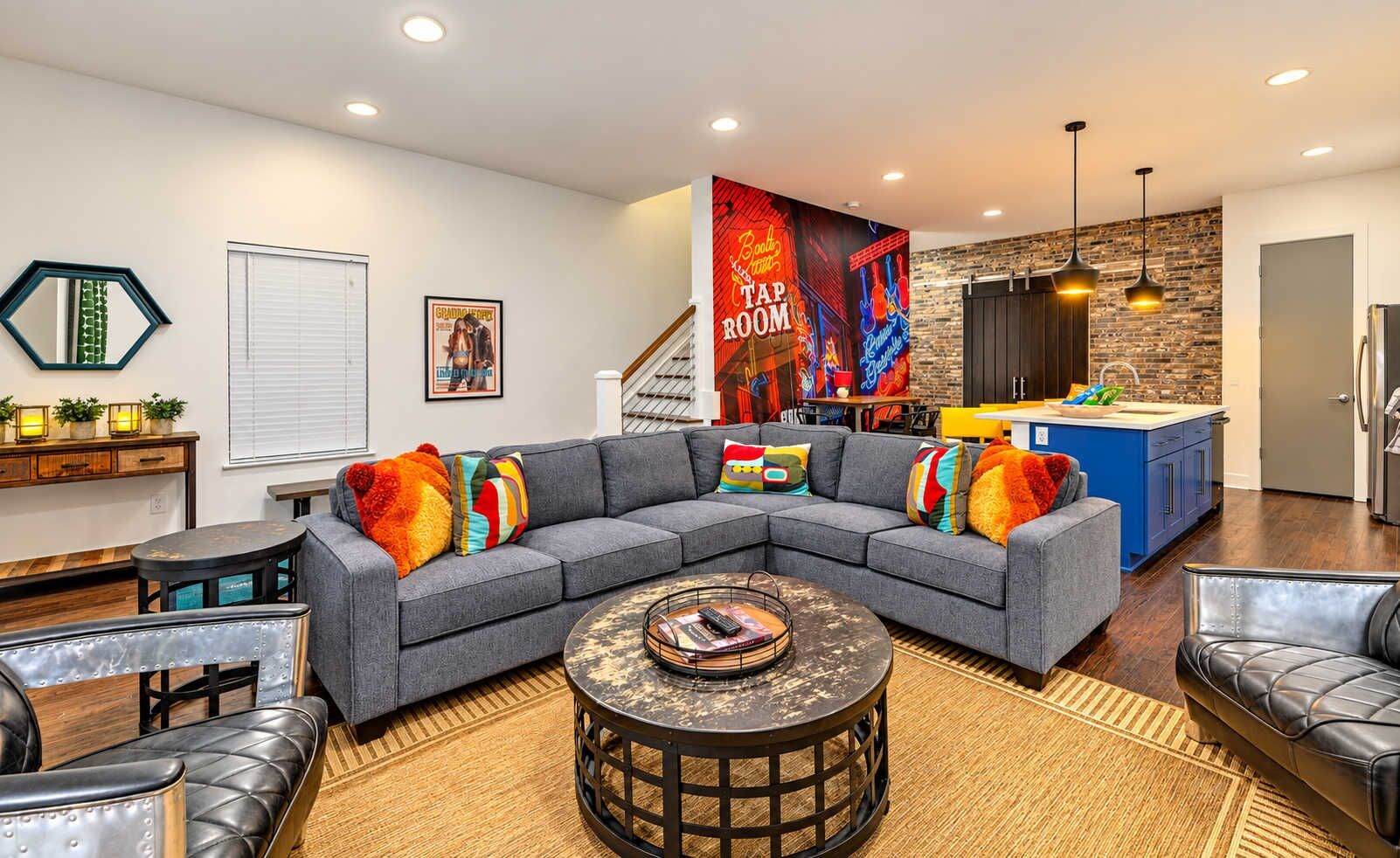 A modern living room with a sectional sofa, a coffee table, and a kitchen area with a blue countertop.