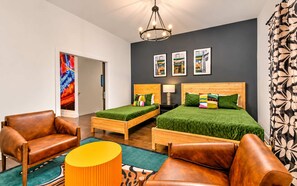 A hotel room with a bed, two bedside tables, a lamp, a chair, and a sofa.