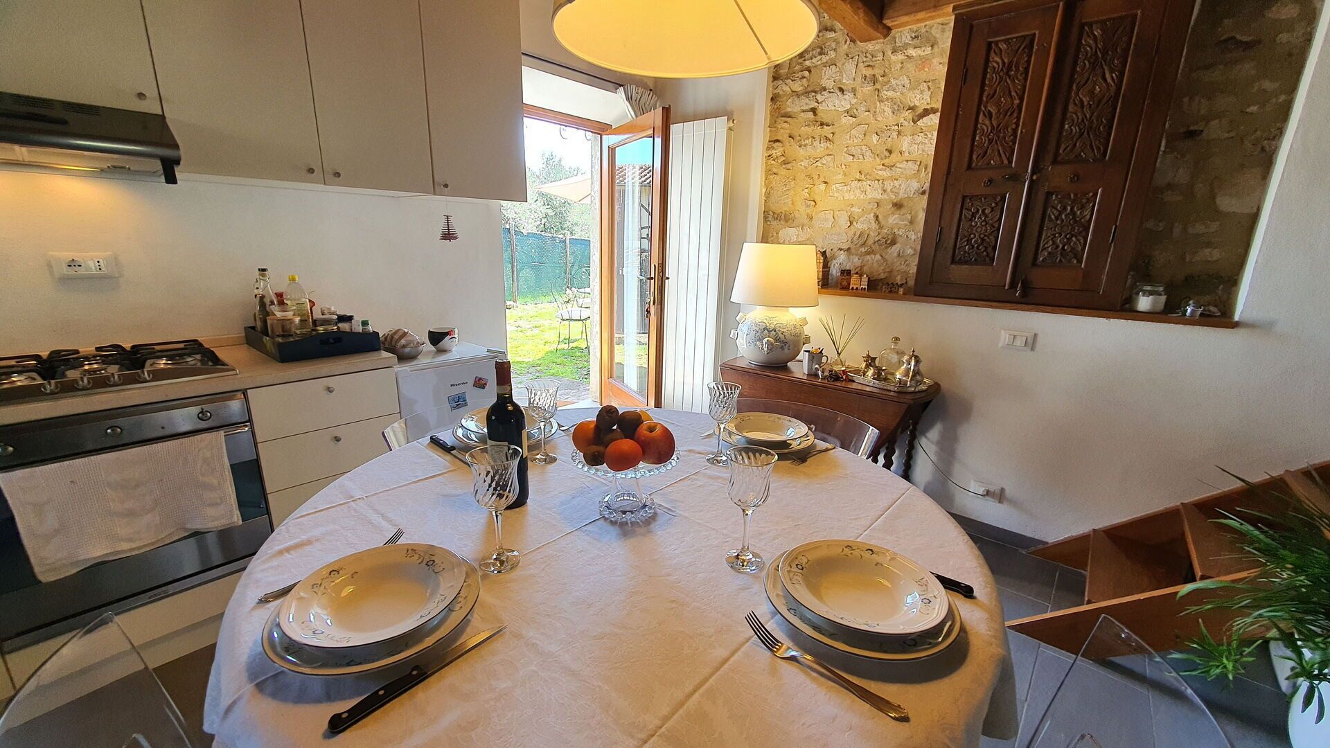 A kitchen with a dining table set for four, a stove, and a view of the garden.