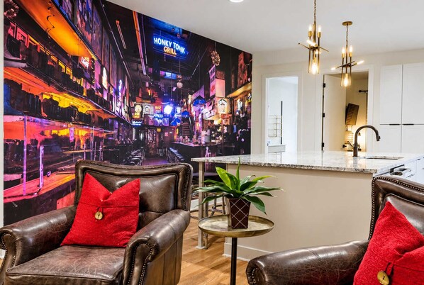 A modern living room with leather armchairs, a small round table, and a vibrant cityscape mural on the wall.