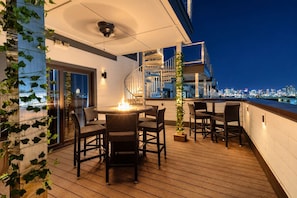 A rooftop terrace with a round table and chairs, a fire feature, and a city skyline view at night. - Luxury Home Amazing Rooftop 11 Beds Pool Table! (Nashville)