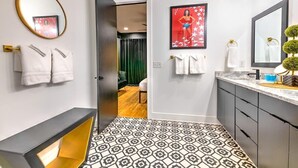 Een moderne badkamer met een patroon vloer, een grote spiegel en een wastafelmeubel met een marmeren aanrechtblad.