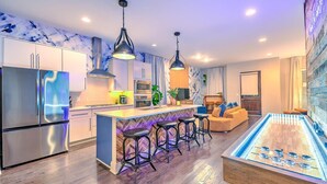 A modern kitchen with a bar area, bar stools, and a foosball table. - Premium Gulch Home 15 Beds Ultimate Skyline Views (Nashville)