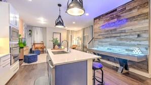A modern kitchen with a central island, pendant lighting, and a neon sign on the wall. - Premium Gulch Home 15 Beds Ultimate Skyline Views (Nashville)