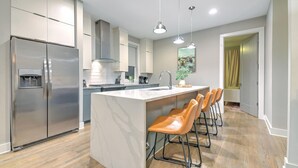Une cuisine moderne dotée d’un grand îlot central, d’appareils électroménagers en acier inoxydable et de tabourets de bar.