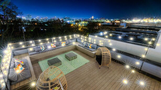 Une terrasse sur le toit, dotée d’une plateforme en bois, d’espaces pour s’asseoir et d’une guirlande lumineuse.