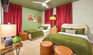 A room with two beds, a desk, a lamp, and a ceiling fan.