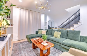Ein Wohnzimmer mit einem grünen Sofa, einem Holztisch und einer Treppe.