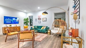 A modern living room with a television, sofa, chairs, and a hanging chair.