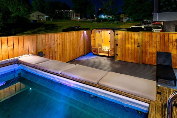 Una bañera de hidromasaje con paredes de madera y un banco integrado, rodeada por una piscina.