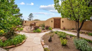 A courtyard with a stone pathway, a wooden door, and a sculpture of a bull. - Casa San Miguel | Santa Fe Sanctuary with Views (Santa Fe)