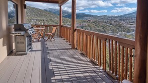 A wooden deck with a grill and chairs, overlooking a mountainous landscape. - Casa San Miguel | Santa Fe Sanctuary with Views (Santa Fe)