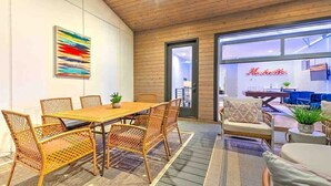 A modern interior with a wooden ceiling, a dining area with wicker furniture, and a view through a glass door. - Lux Home • 13 Beds • Walk 2 Restaurants • Rooftop (Berry Hill)