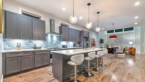A modern kitchen with grey cabinets, a central island with bar stools, and pendant lighting. - Lux Home • 13 Beds • Walk 2 Restaurants • Rooftop (Berry Hill)
