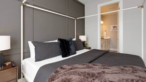 Un letto a baldacchino con una testiera scura, una coperta marrone e due comodini con lampade.