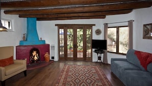 Een woonkamer met een open haard, een bank, een televisie en een groot raam.
