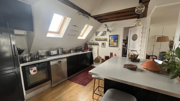 A modern kitchen with skylights, a central island, and a dining area. - Charming Apartment in the Heart of Paris. Families are Welcome (Paris)