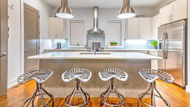 A modern kitchen with a central island, stainless steel appliances, pendant lighting, and three bar stools. - Huge 4 Bedroom Home 14 Big Beds Rooftop Deck (Nashville)